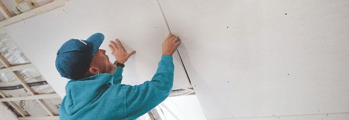 Handwerker verkleidet eine Dachschräge mit Gipskartonplatten.